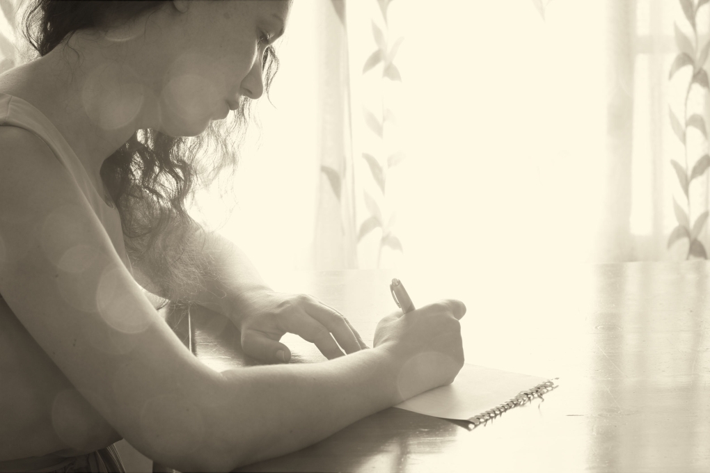 Девушка пишет письмо у окна